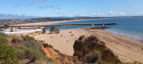a beach with people on the sand and a bridge at Casa Afonso in Lagos