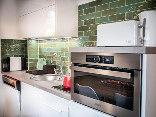 a kitchen with an oven with a sink and a counter at Ugo Apartman in Halászi