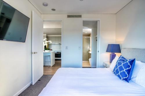 a bedroom with a large white bed with blue pillows at Inspire Boutique Apartments in Toowoomba