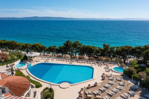 uma vista superior de uma piscina e do oceano em Bluesun Holiday Village Afrodita em Tučepi