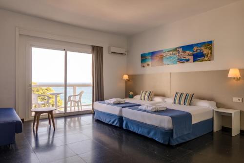 a hotel room with two beds and a balcony at htop Caleta Palace #htopBliss in Platja d'Aro