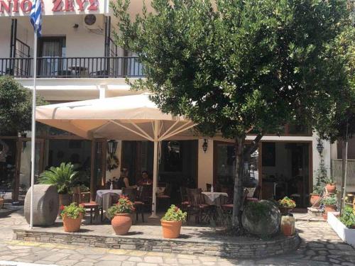 un restaurante con mesas y sillas y una sombrilla grande en Xenios Zeus en Ouranoupoli