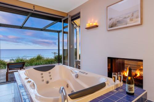 a bath tub in a room with a fireplace at Chocolate Gannets in Apollo Bay