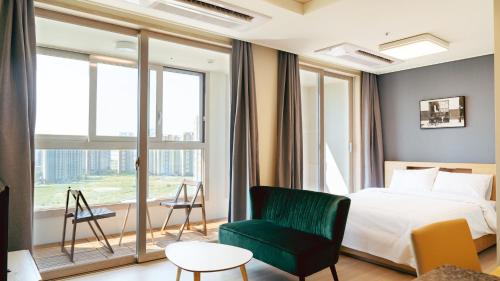 a bedroom with a bed and a green chair at The November Stay In landmark in Incheon