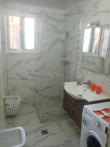 uma casa de banho com um chuveiro, um lavatório e uma máquina de lavar roupa em Saranda Backpackers em Sarandë