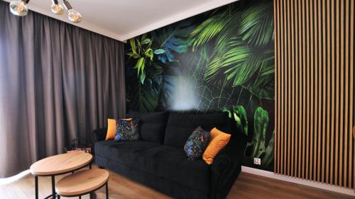 a living room with a black couch and a table at Residence Polanica z sauną, Sun & Snow in Polanica-Zdrój