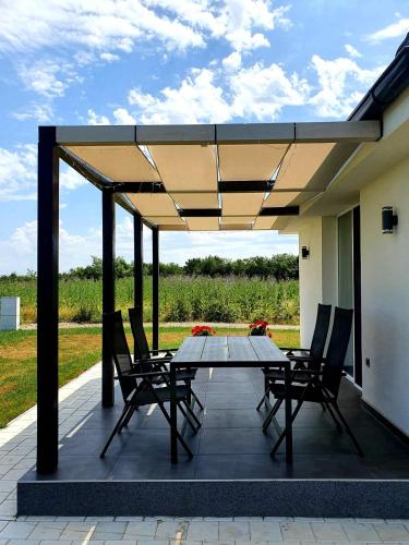 a patio with a table and chairs under a roof at KoVeL apartmani - Termalna Rivijera in Bogatić