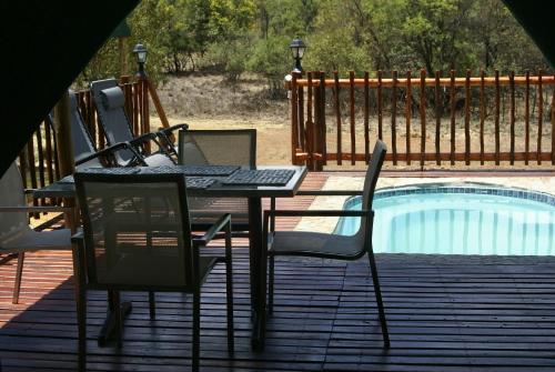 una mesa y sillas en una terraza junto a una piscina en Beka Idube Bushveld Retreat, en Cullinan