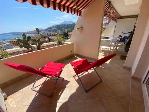 two red chairs sitting on the balcony of a house at Mansfield vue carte Postale Terrasse Piscine calme port à 200m à pied in Menton