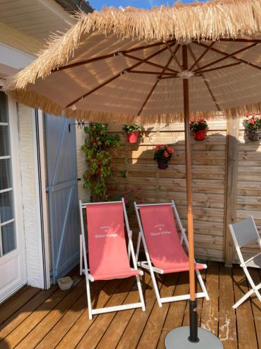 two chairs under an umbrella on a deck at Nature Et Plage in Audembert