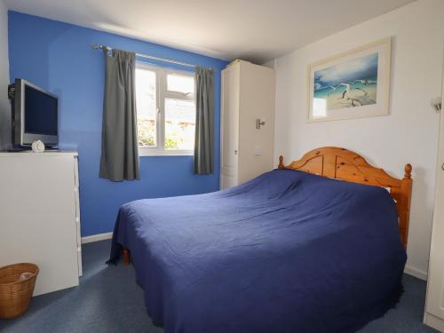 a blue bedroom with a bed and a television at Trevone - Chalet 130 in Padstow