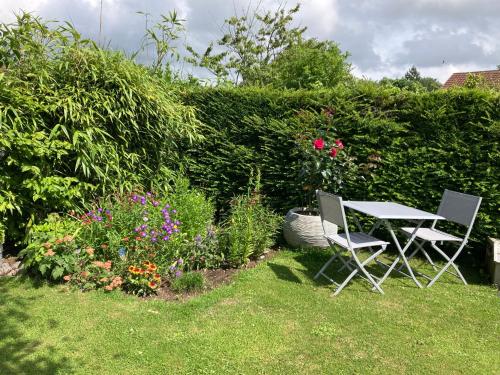 a table and two chairs in a garden with flowers at Nature Et Plage in Audembert