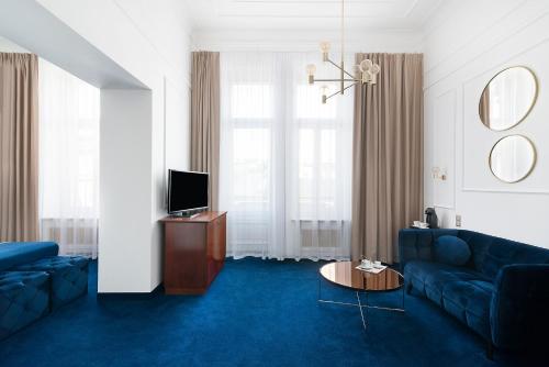 a living room with a blue couch and a tv at IBB Hotel Grand Hotel Lublin in Lublin