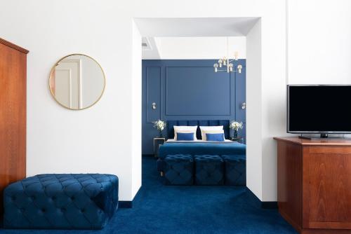 a bedroom with a blue bed and a tv at IBB Hotel Grand Hotel Lublin in Lublin