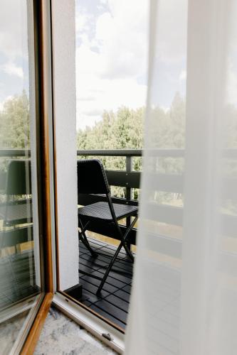 a chair sitting on a balcony looking out a window at Green Town in Vievis