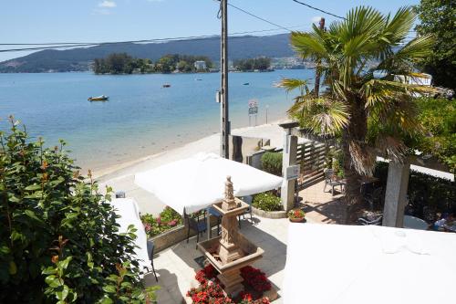 a view of a beach with a white table and benches at Hostal Antolín in Redondela