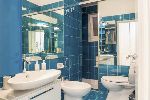 - une salle de bains carrelée de bleu avec 2 toilettes et un lavabo dans l'établissement Eden Vista Mare by Wonderful Italy, à Gênes