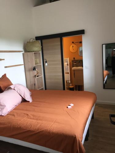 a bedroom with a large bed with an orange blanket at GITE COCOTTE in Pierrerue