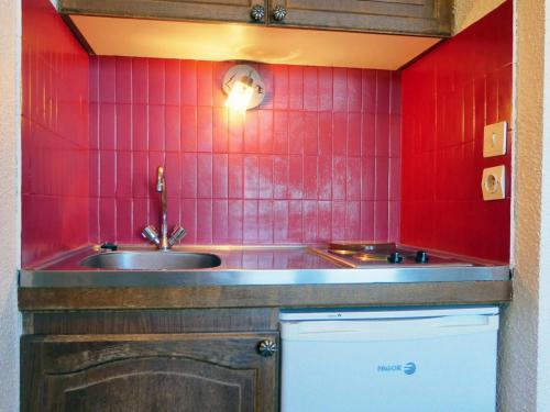 a kitchen with a sink and a red tiled wall at Studio Méribel, 1 pièce, 3 personnes - FR-1-182-43 in Méribel