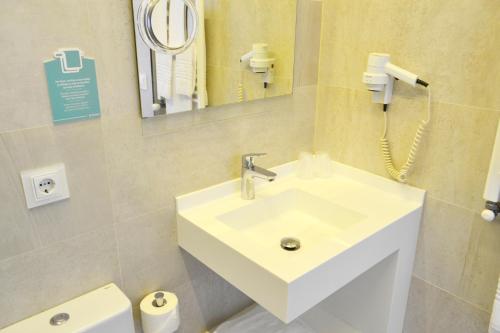 a bathroom with a sink and a mirror and a toilet at Hotel Alda San Bieito in Santiago de Compostela