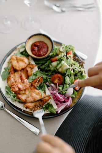 a plate of food with shrimp and salad and a bowl of sauce at Green Town in Vievis