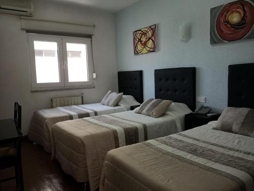a hotel room with three beds and a window at Hotel 4 Estacoes in Chaves