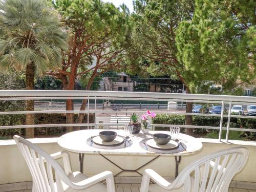 a white table and chairs on a balcony with trees at Apartment Golden Gates by Interhome in Cannes