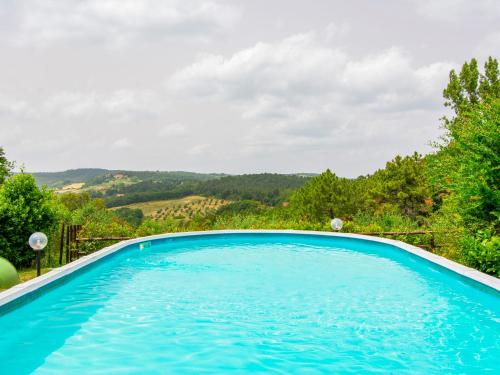 uma grande piscina azul com árvores e montanhas ao fundo em Holiday Home L'Antica Chiesa by Interhome em Camporbiano