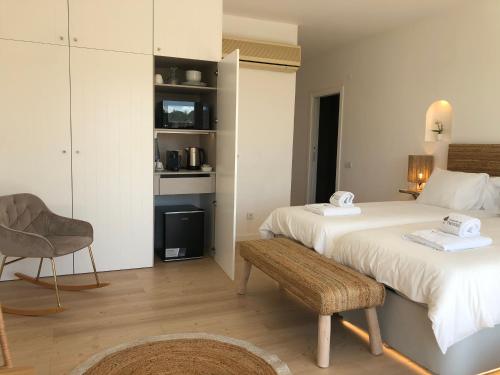 a bedroom with two beds and a chair and a table at Herdade Do Freixial - Turismo Rural in Vila Nova de Milfontes