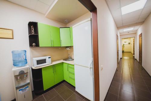 a small kitchen with green cabinets and a microwave at Podkova Omsk in Omsk