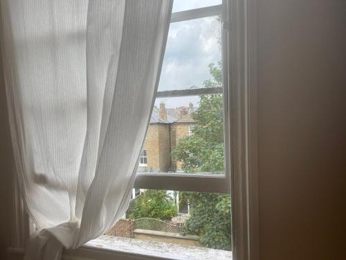 an open window with a view of a house at Guest House quarto cama box Finsbury Park in London