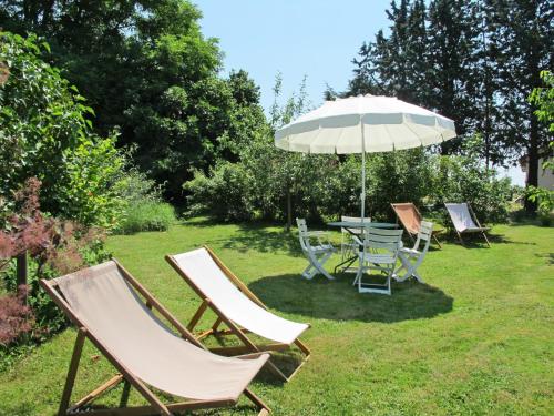 a group of chairs and a table with an umbrella at Holiday Home La Janverie - MNX200 by Interhome in Monteaux