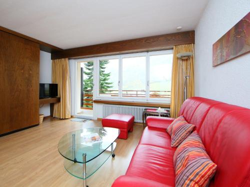 a living room with a red couch and a glass table at Apartment Ringstrasse - Utoring-7 by Interhome in Leukerbad