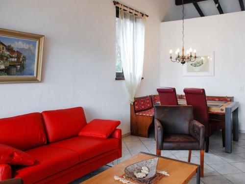 ein Wohnzimmer mit einem roten Sofa und einem Tisch in der Unterkunft Apartment Miralago - Utoring-17 by Interhome in Piazzogna