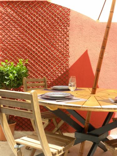 une table en bois avec deux chaises et un verre de vin dans l'établissement La Terrasse du Marché aux Fleurs, à Montpellier