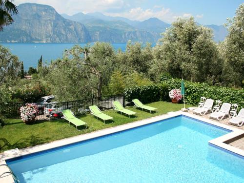 a swimming pool with chairs and a view of a lake at Apartment Delvai-1 by Interhome in Brenzone sul Garda