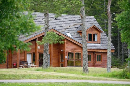 a house that has a tree in front of it at Badaguish forest lodges, eco camping pods and tent camping in Aviemore