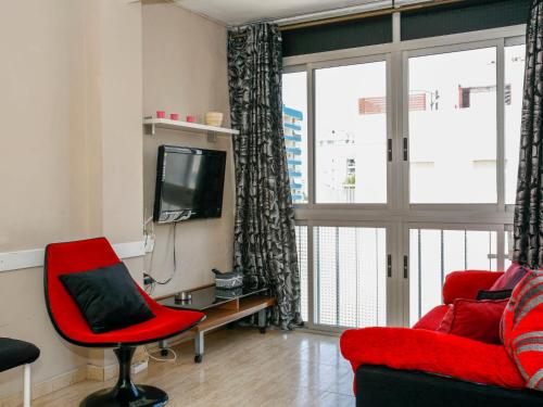 a living room with a red chair and a tv at Apartment Solmar by Interhome in Gandía
