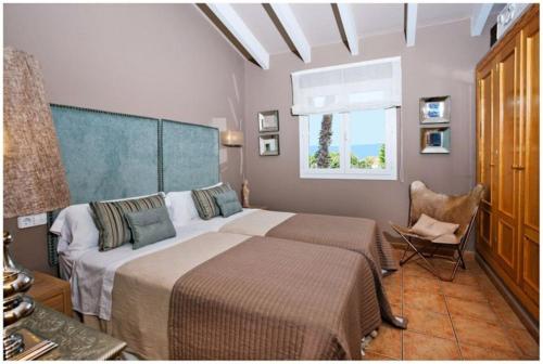 1 dormitorio con 2 camas, silla y ventana en BINI CEL for 6 pax Heated Pool on request, en Binibeca