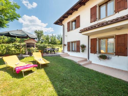 a backyard with two chairs and an umbrella at Holiday Home Il Castelliere-2 by Interhome in Rive dʼArcano