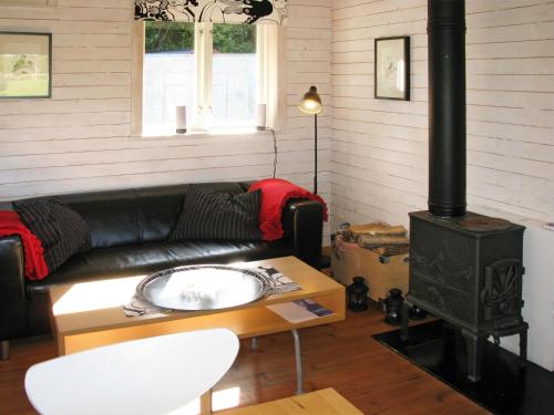 a living room with a black leather couch and a wood stove at Chalet Grönede - OST006 by Interhome in Kisa