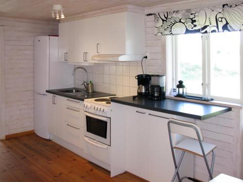 una cucina bianca con piano cottura e lavandino di Chalet Grönede - OST006 by Interhome a Kisa
