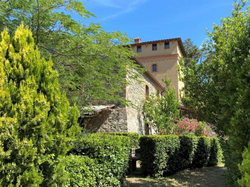 un jardín con arbustos y un edificio de fondo en Apartment Volpe by Interhome, en Riparbella