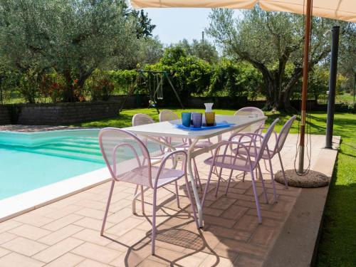 una mesa con sillas y una sombrilla junto a la piscina en Villa Casal di Yuri by Interhome, en Vetralla