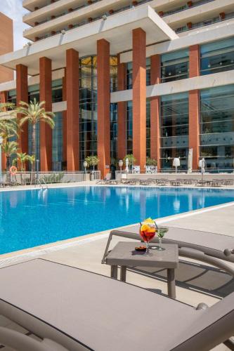 a swimming pool with a table in front of a building at Hotel BCL Levante Club & Spa 4 Sup - Only Adults Recomended in Benidorm