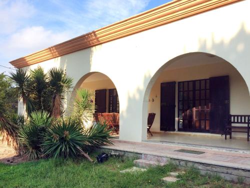 una casa con arcos y palmeras en el patio en Holiday Home Goleri - BSD100 by Interhome, en Bari Sardo
