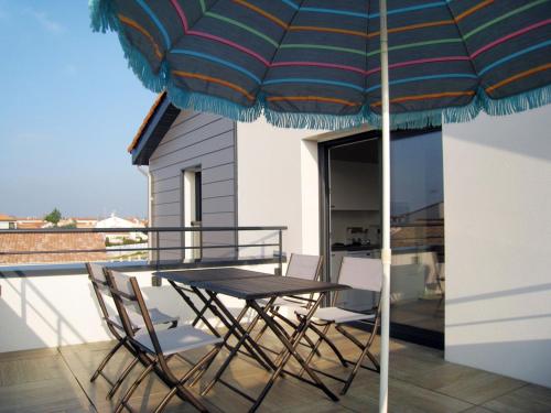 聖吉爾－克魯瓦德維的住宿－Apartment Les Epinettes by Interhome，阳台配有桌椅和遮阳伞