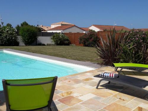 uma piscina com duas cadeiras verdes ao lado em Apartment Les Epinettes by Interhome em Saint-Gilles-Croix-de-Vie