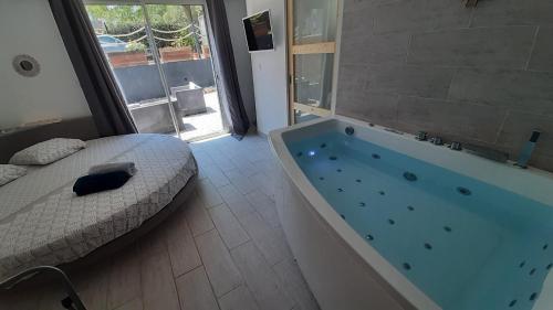 Allegria Nimes Chambre Deluxe Spa في نيم: غرفة نوم مع سرير وحوض استحمام في غرفة