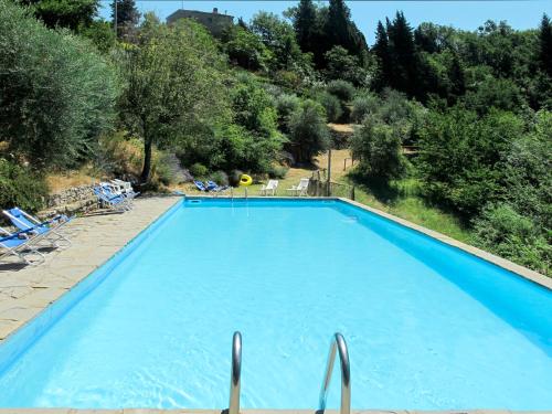 einen großen blauen Pool mit Stühlen und Bäumen in der Unterkunft Villa San Leolino by Interhome in Londa